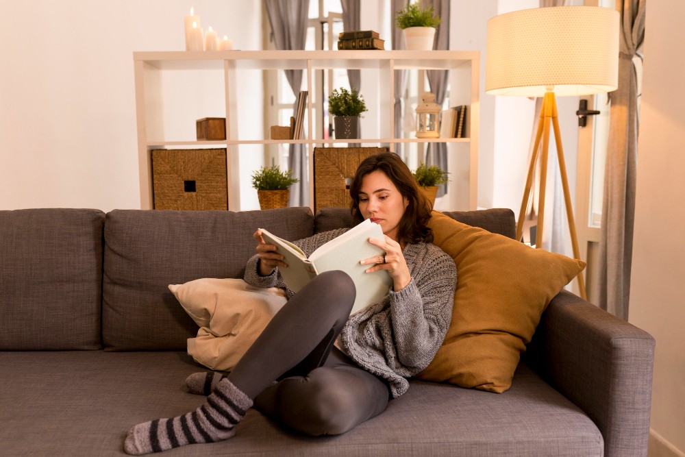 žena si číta knihu v obývačke na pohovke
