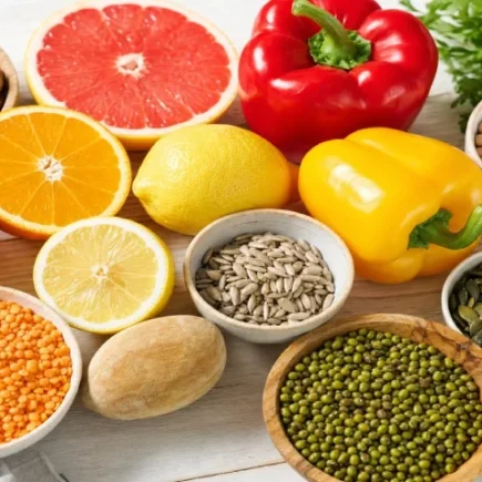 Čerstvé potraviny bohaté na vitamín C a zinok - citrusy, paprika, orechy, semienka a strukoviny na svetlom drevenom stole